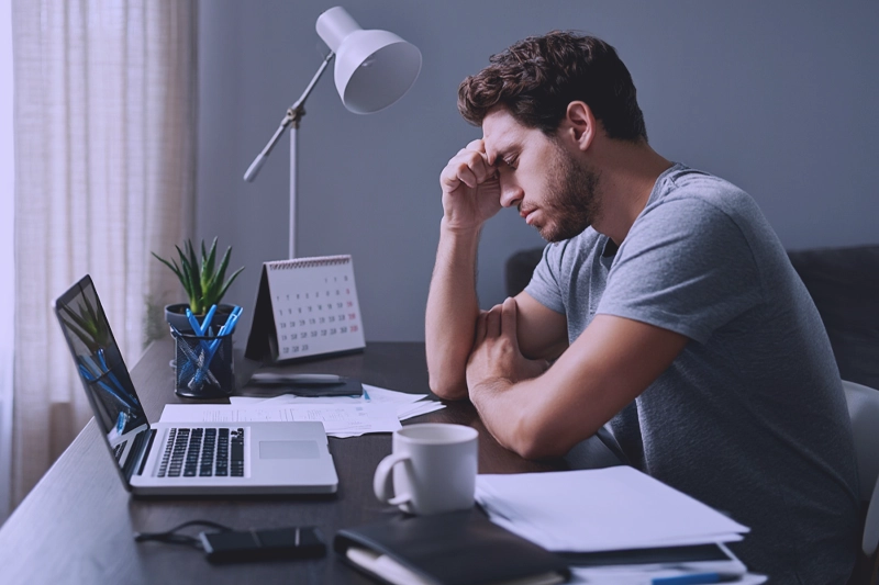 Мужчина сидит за столом с кучей работы